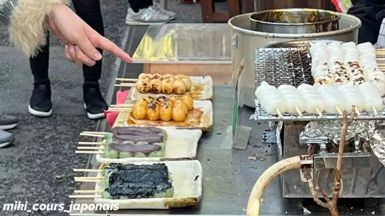 Stand de rue au Japon : brochettes de dango (お団子) à la sauce soja, à la pâte de haricots rouges et à l’algue nori, avec des dango blancs en train de griller.