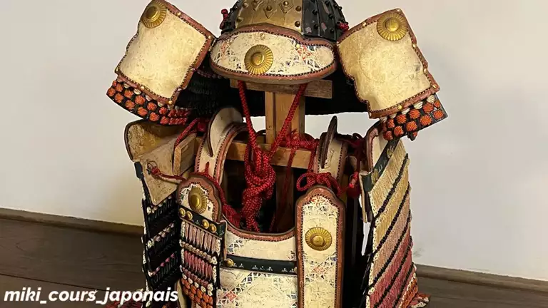 Armure de samouraï japonaise (甲冑, kacchū) avec casque, plaques dorées et cordons rouges.