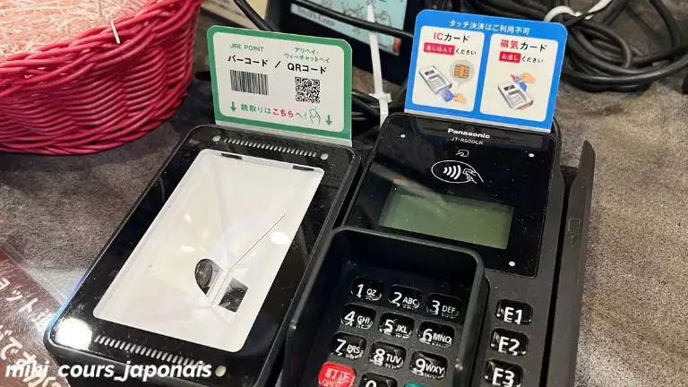 Caisse d'un restaurant au Japon (お会計) : scanner de QR code et de code-barres à gauche, terminal de paiement par carte à droite.